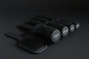 Five black hairbrushes from the brand EVY, including three round brush styles and two paddle brush styles, arranged on a light gray background.