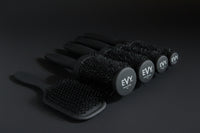 Five black hairbrushes from the brand EVY, including three round brush styles and two paddle brush styles, arranged on a light gray background.